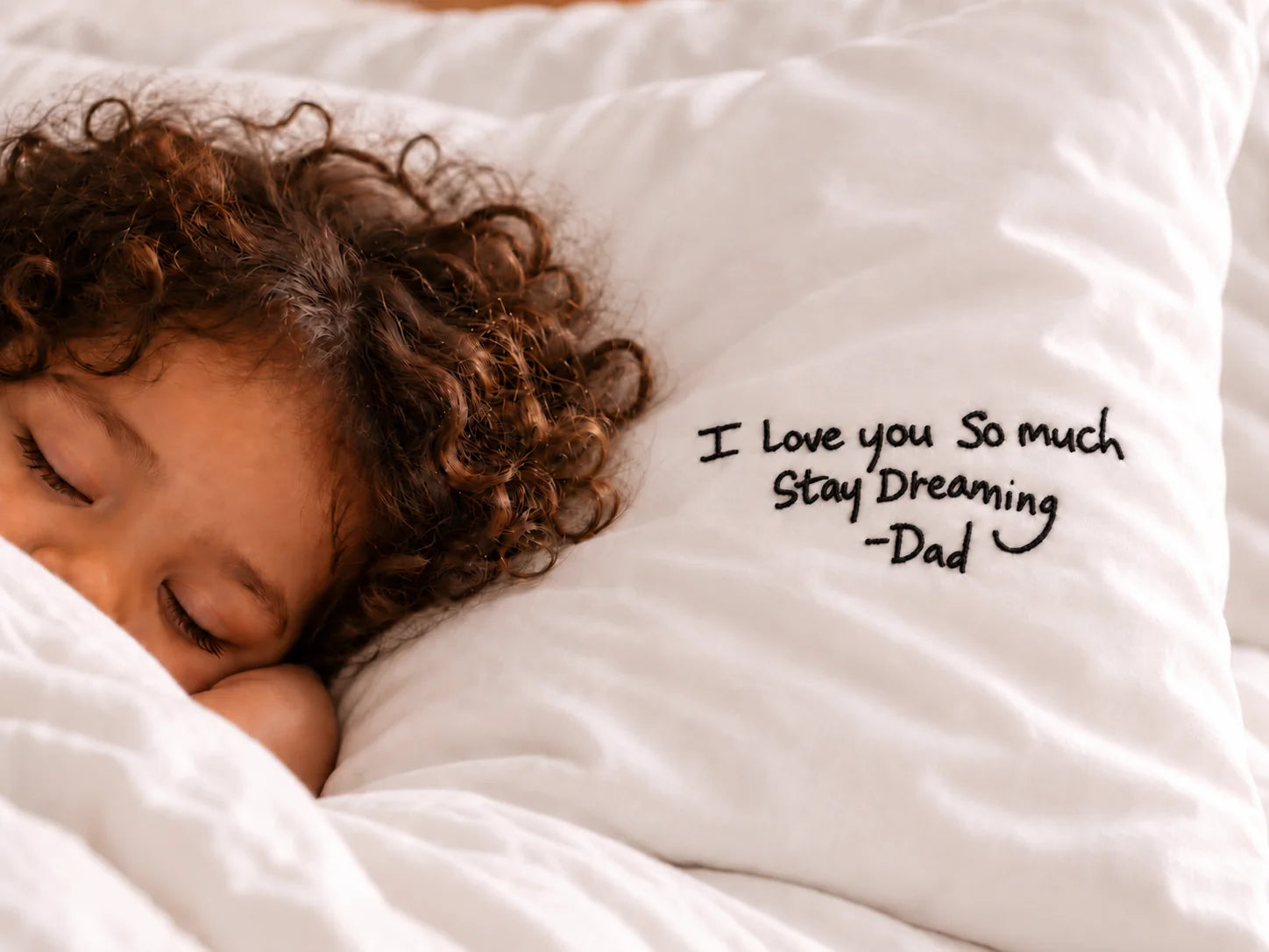 A child beside a handwritten message on a white cotton pillow